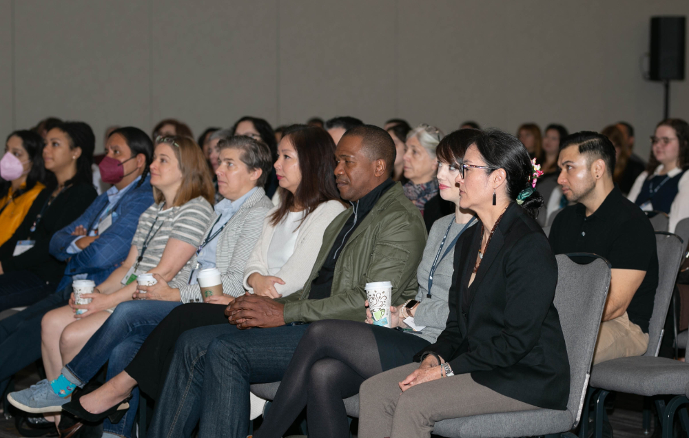 People sitting in chairs watching at the 2023 annual business meeting