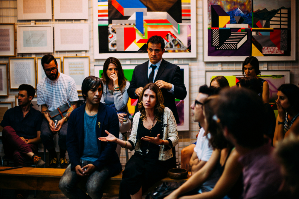 People sitting on chairs in a room with art on the walls having a discussion