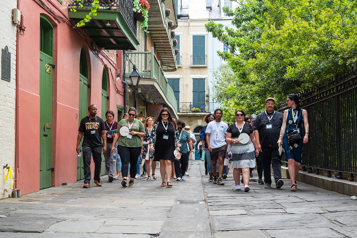 A group of more than two dozen teachers walking down a typical historic New Orleans street towards the camera.